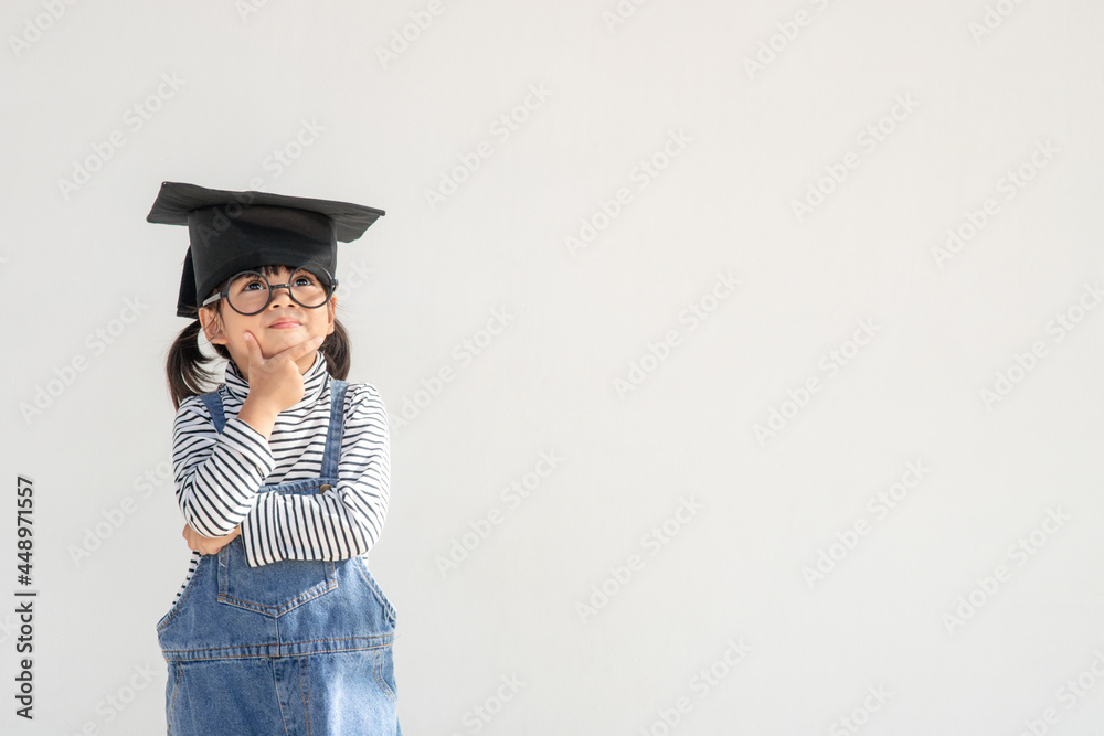 Happy Asian school kid graduate thinking with graduation cap Happy Asian school kid graduate thinking with graduation cap