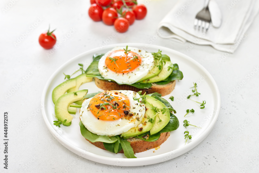 Fried eggs, avocado and greens on toasted bread Fried eggs, avocado and greens on toasted bread