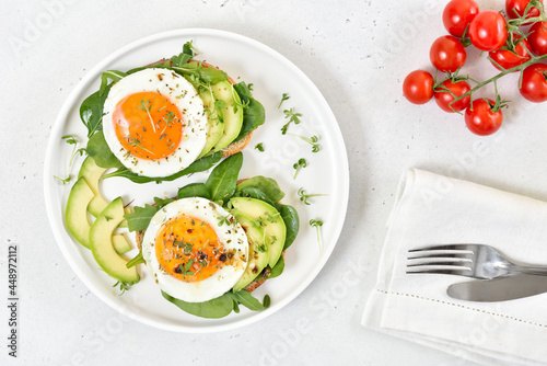 Bread with fried eggs, avocado and greens. Healthy breakfast