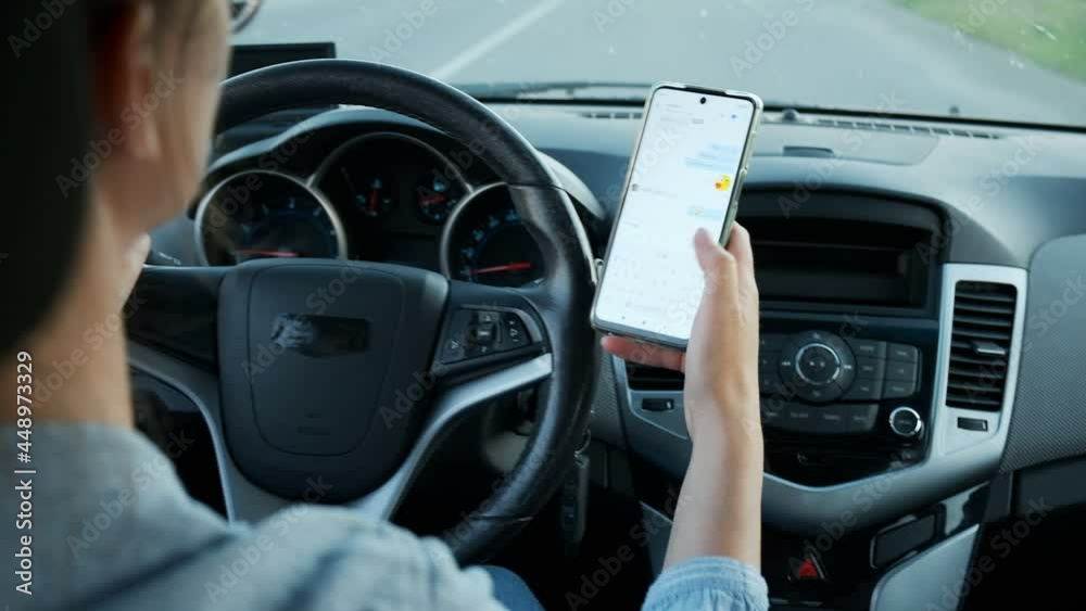 Woman driving car texting message on mobile phone in motion, don't text and drive