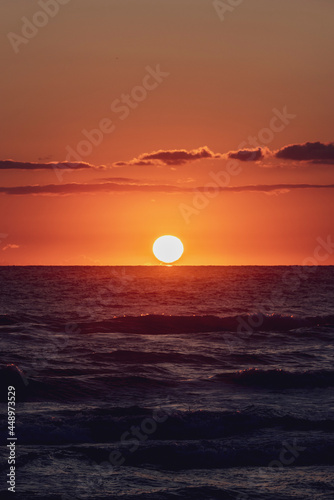 Fototapeta Naklejka Na Ścianę i Meble -  Amanecer en la playa con vistas al Mar Mediterráneo con cielo anaranjado y nublado.