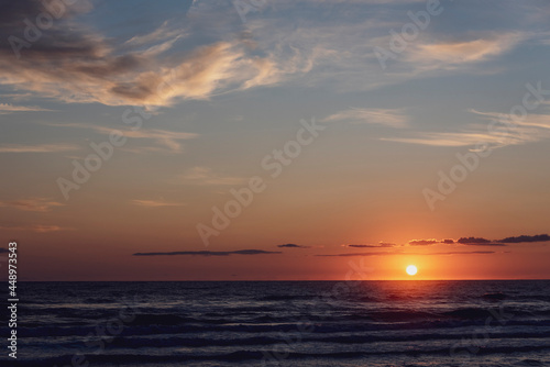 Amanecer en la playa con vistas al Mar Mediterráneo con cielo anaranjado y nublado. © jfreplica