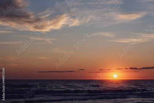 Amanecer en la playa con vistas al Mar Mediterr  neo con cielo anaranjado y nublado.