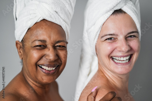 Multiracial senior women with diverse skin and body laughing together while wearing body towels - Main focus on right female face
