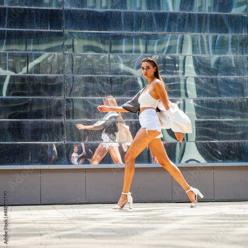 Portrait of a young beautiful brunette woman walking in summer street