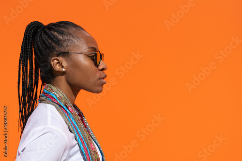Tableau sur toile Retrato de perfil de chica africana con expresión de tristeza, con espacio para texto en fondo naranja