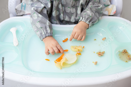 Top view hands of baby sitting on dining table eat food by her self, Baby-Led Weaning concept