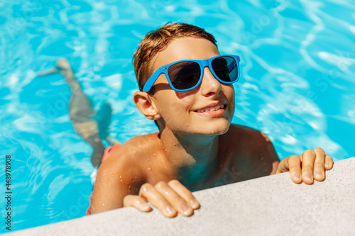 Little boy in sunglasses swimming in the pool having fun, Happy child playing in the pool, Summer vacation concept, Top portrait
