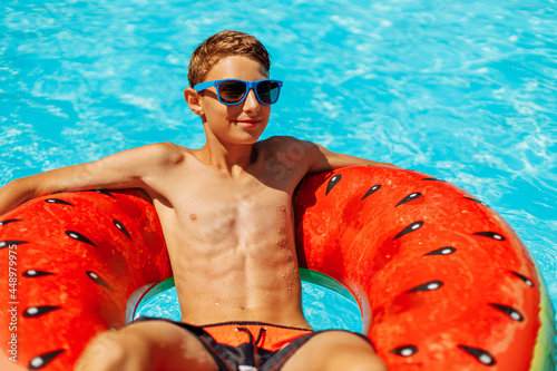 Happy little boy swims with colorful inflatable ring in outdoor pool on hot summer day, Kids toys with water, Kids play in tropical resort