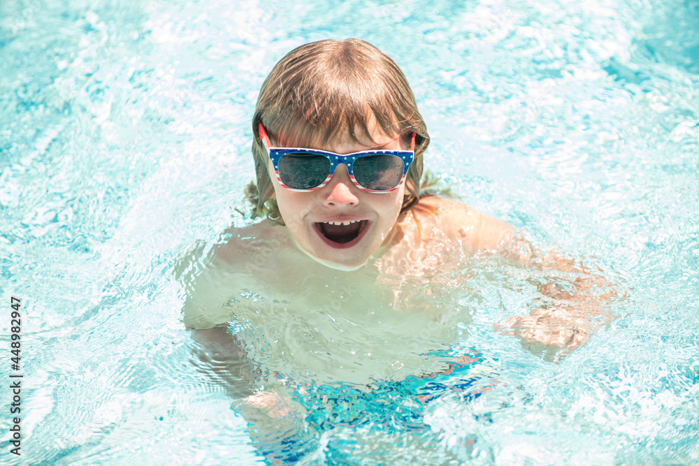 happy child boy in glasses swimming in pool, summer vacation