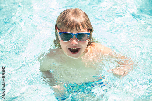 happy child boy in glasses swimming in pool, summer vacation