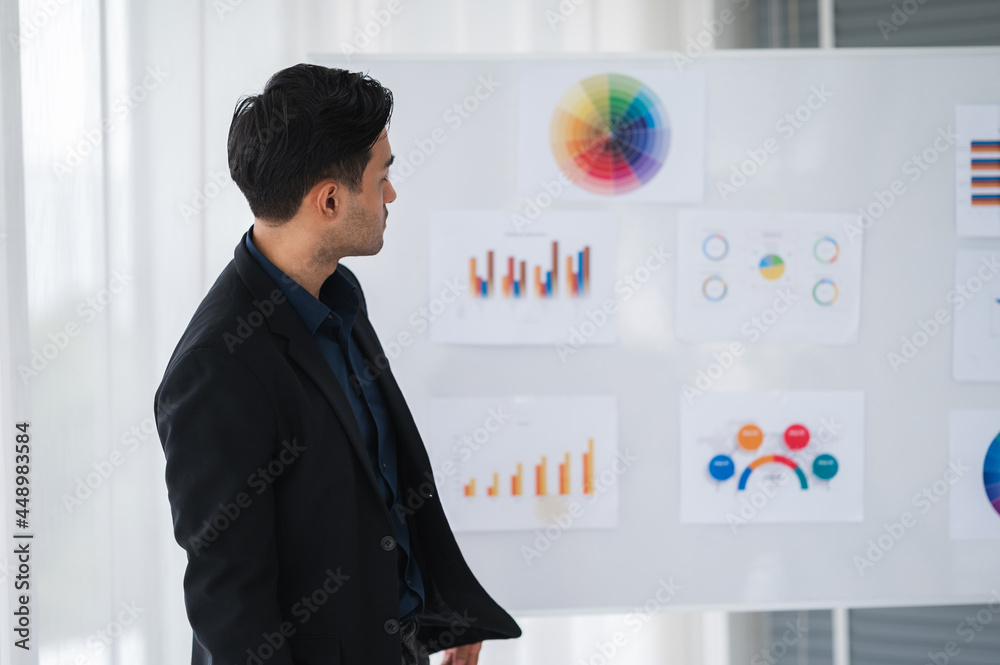 Fototapeta premium Businessman or manager presents a discussion graph, a strategic planning report, and discusses ways to increase profits with colleagues at the workshop. Brainstorming and teamwork concept.