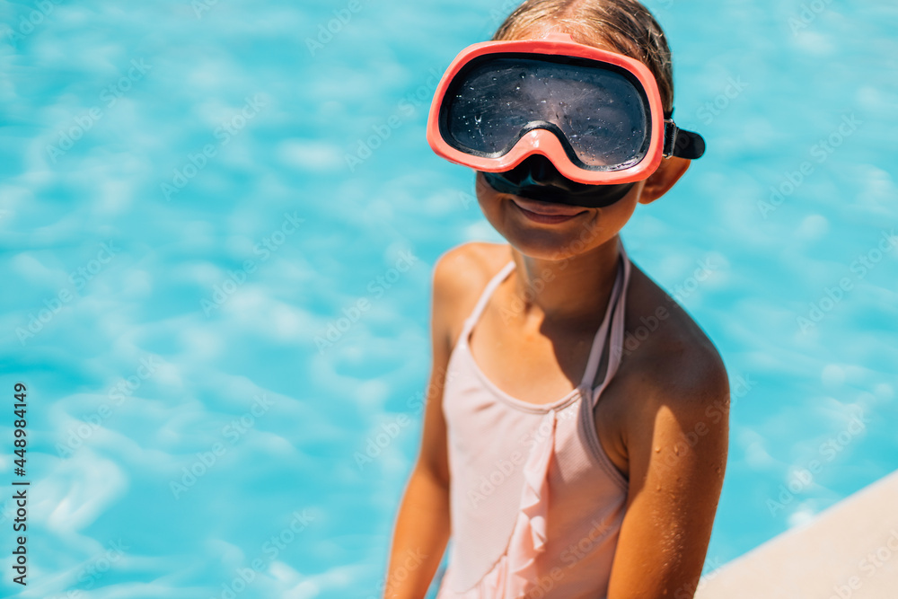 Smiling cute girl in goggles for swimming, in the pool on a sunny summer day, the concept of summer vacation