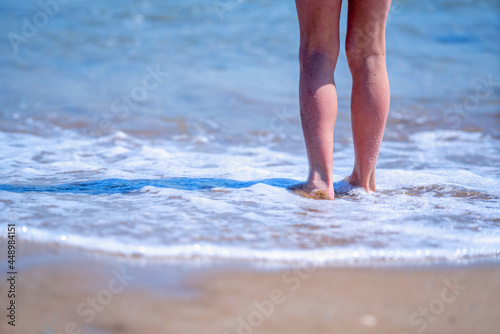 Portrait of beautiful young girl standing in blue sea water. Summer holiday and rest concept. Copy space for design or text.