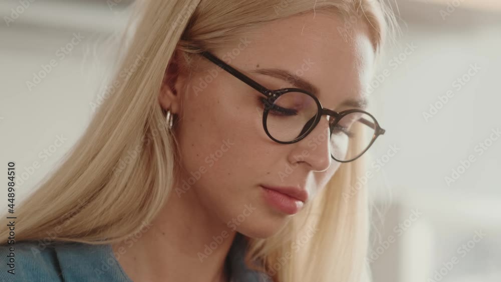 A close-up view of a woman's face is writing sitting at the table A close-up view of a woman's face is writing sitting at the table
