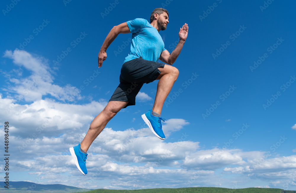 muscular man running in sportswear outdoor on sky background, challenge