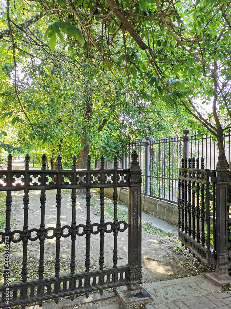 A cast-iron fence and a gate leading to the Catherine Park of the city of Kronstadt against the background of a blue cloudless sky. A cast-iron fence and a gate leading to the Catherine Park of the city of Kronstadt against the background of a blue cloudless sky.