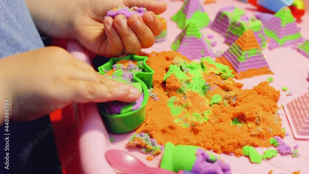 The child sculpts figures from multi-colored kinetic sand, developing fine motor skills of hands The child sculpts figures from multi-colored kinetic sand, developing fine motor skills of hands