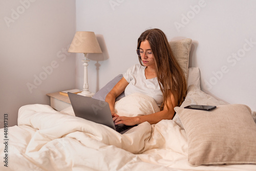 Young latin woman with computer in the bed