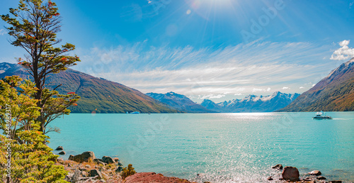 Panoramic view over glacial lagoon near gigantic Perito Moreno glacier in Patagonia with blue sky, turquoise water with icebergs and tour boats with tourists, South America, Argentina, at sunny day.