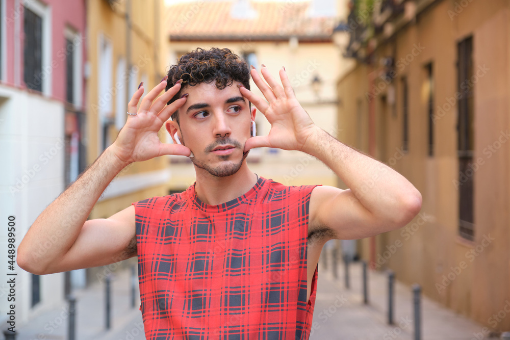 Portrait of a young caucasian man with long false nails posing.