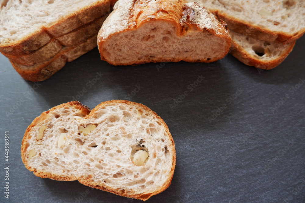 Close-up image of a bread cutting on a black background. Healthy baked bread, whole bread on dark background. Close-up image of a bread cutting on a black background. Healthy baked bread, whole bread on dark background.
