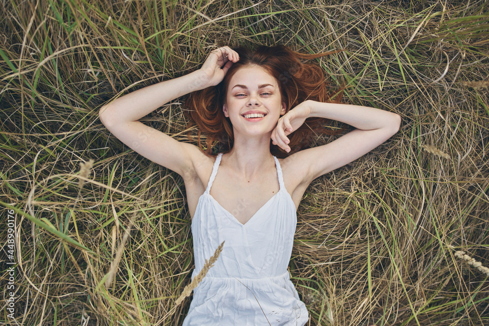 A woman in a white dress lies on the grass nature relaxation sun top view