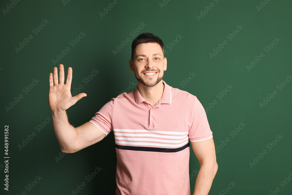 Cheerful man waving to say hello on green background Cheerful man waving to say hello on green background