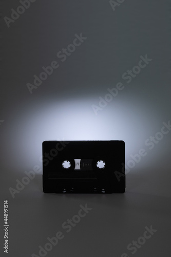 Audio cassette close up, centered on dark grey background with spot of light on it. Analog Audio Tape.