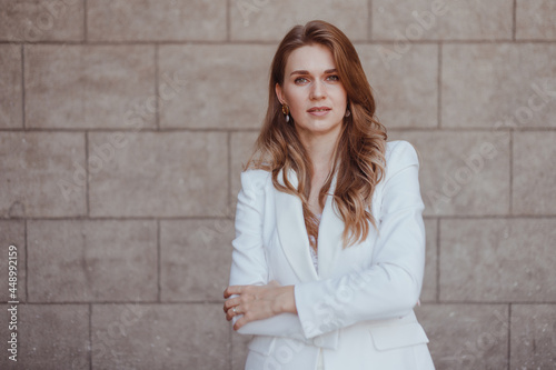 Business woman in white suit posing with crossing arms