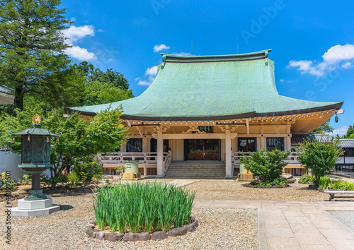 Concrete architecture of the main hall or hondo of buddhist gotokuji zen temple dedicated to Japanese Manekineko cat with a gold bronze octagonal lantern and a flowerbed. photo