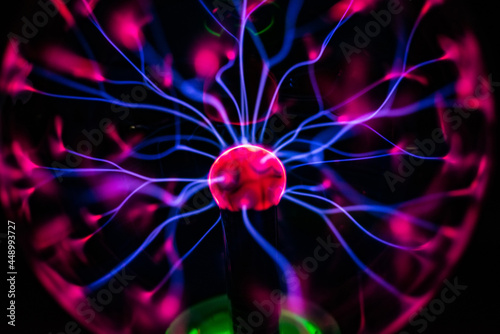 Plasma ball with smooth magenta-blue flames isolated on a black background. photo