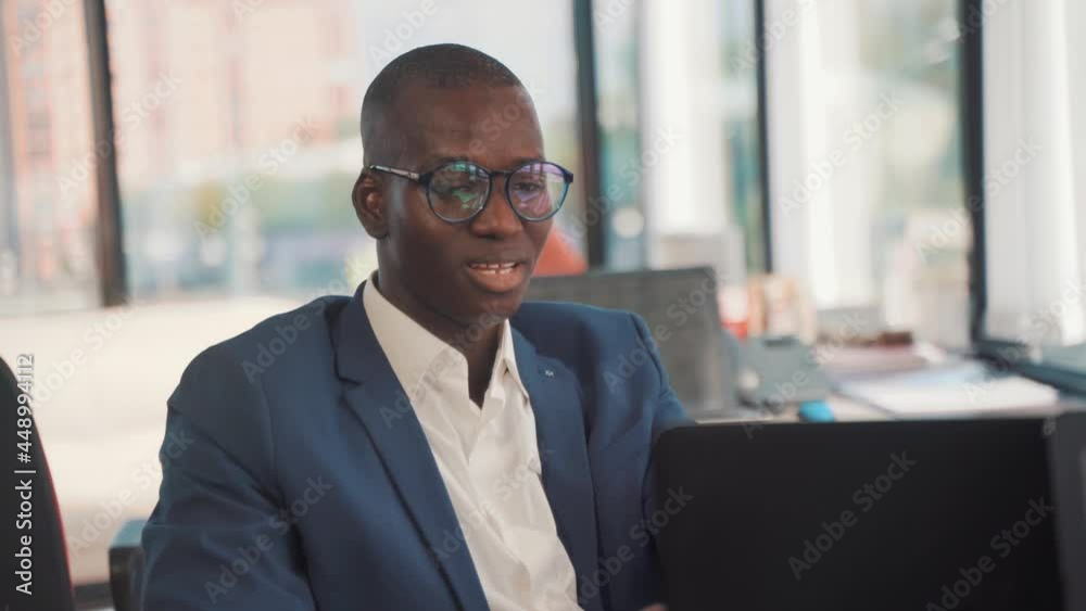 African ethnicity office worker working at computer indoors in office. Concept of leadership, successful entrepreneur, happy manager, salesman broker or financial advisor concept African ethnicity office worker working at computer indoors in office. Concept of leadership, successful entrepreneur, happy manager, salesman broker or financial advisor concept