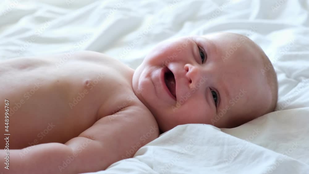 Portrait of Newborn. Beautiful Baby Face Close up. Small Child smiles and laughs. Cute little Baby is looking into the Camera. Newborn Health. Infancy, Childhood, and Health Concept. 4K Portrait of Newborn. Beautiful Baby Face Close up. Small Child smiles and laughs. Cute little Baby is looking into the Camera. Newborn Health. Infancy, Childhood, and Health Concept. 4K