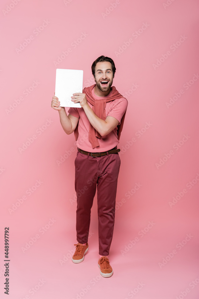 Full length of cheerful man holding laptop on pink background Full length of cheerful man holding laptop on pink background