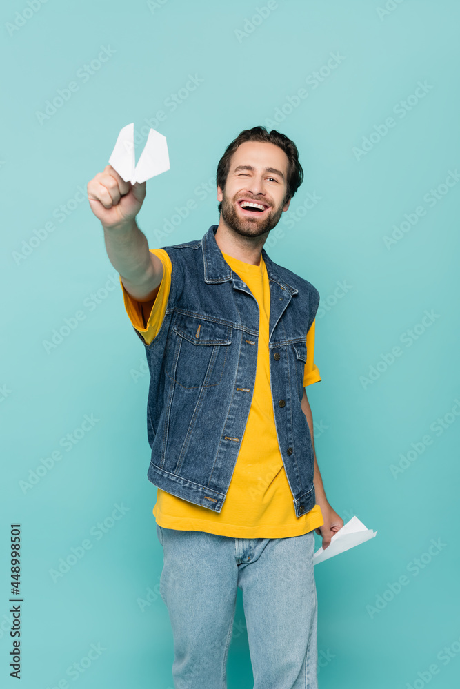 Smiling man holding paper planes isolated on blue Smiling man holding paper planes isolated on blue