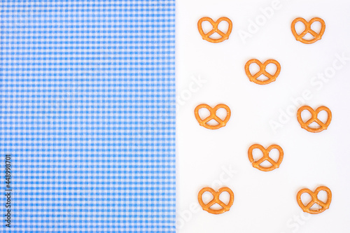 Oktoberfest with a blue and white tablecloth and pretzels on a white background