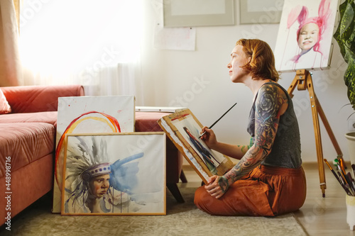 Obraz na plátne Creative red-haired girl hipster woman with paintings in home workshop, girl dra