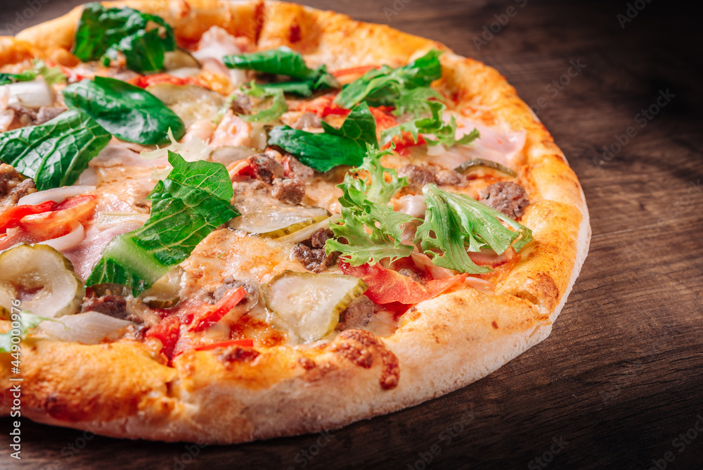 Pizza with cheese, Bolognese sauce, minced meat, bacon, tomato and vegetables. Italian pizza on wooden background.