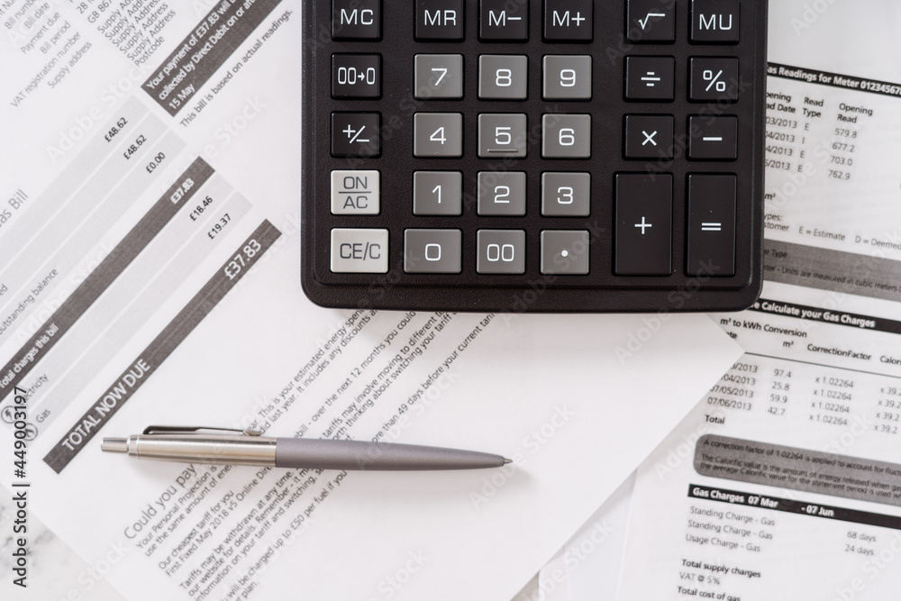 Calculator with pen laying on invoices and bills Calculator with pen laying on invoices and bills