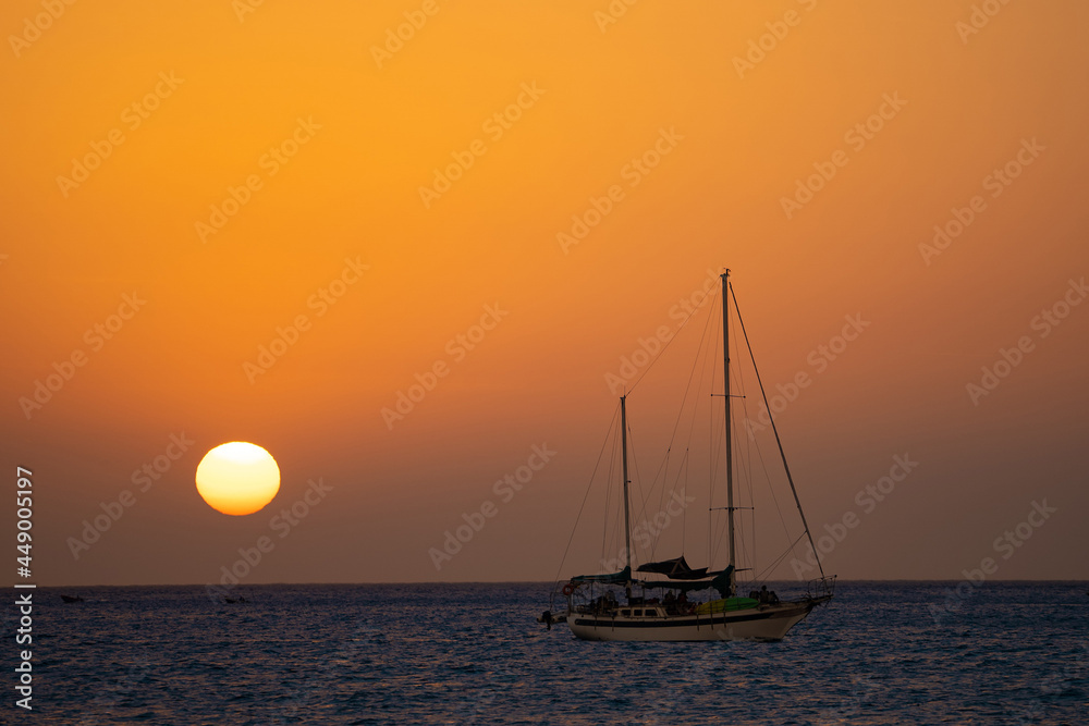 Beautiful sunset with silhouette of sailboat and sun disc. Travel and adventure concept 