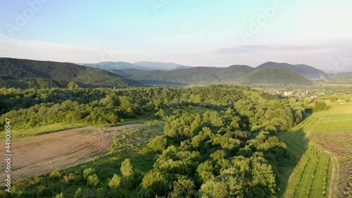 Camera over the forest, among the mountains at sunset