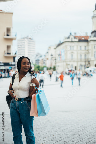 African american woman holding shopping bags and using smartphone