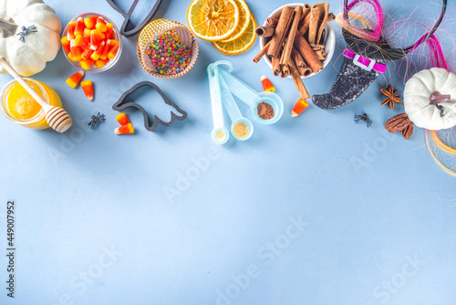 Halloween Gingerbread Cookies cooking background. Autumn holiday baking concept, ingredients, spices, halloween symbol cookie cutters - pumpkin, ghost, bat, witch hat, top view blue table copy space