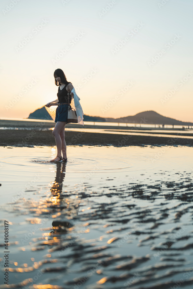 Fototapeta premium 夕暮れの海にいる女性