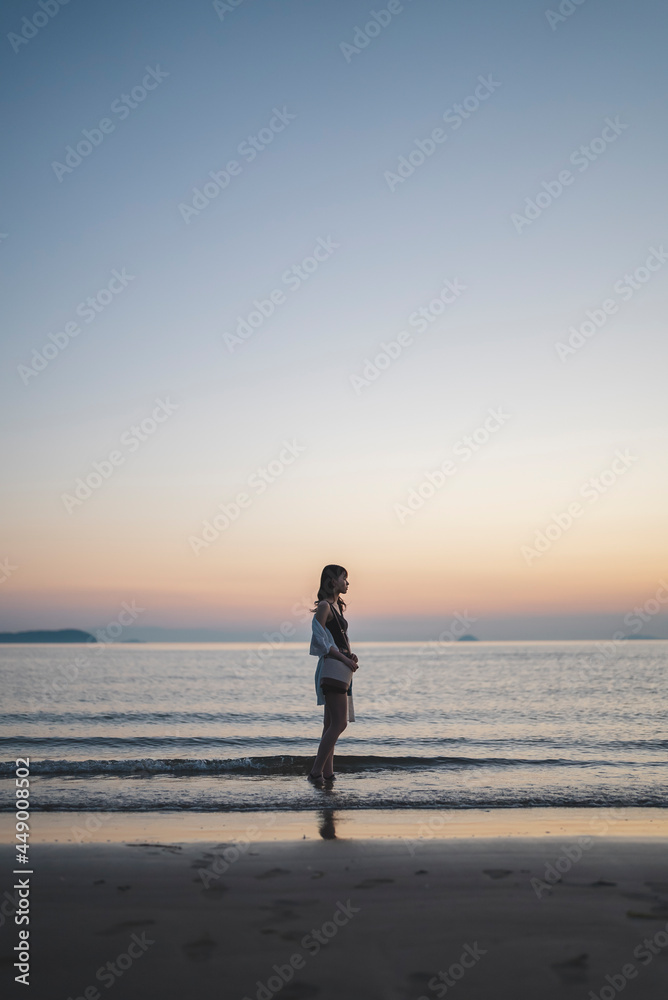 Naklejka premium 夕暮れの海にいる女性