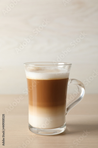 Hot coffee with milk in glass cup on wooden table
