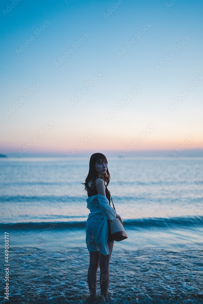 夕暮れの海にいる女性