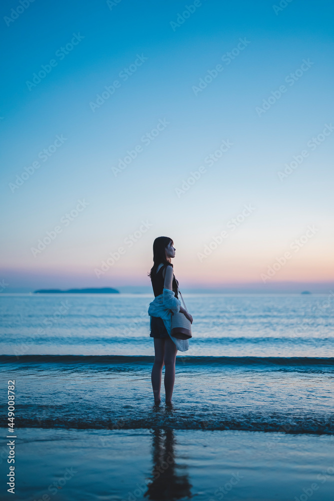 Fototapeta premium 夕暮れの海にいる女性