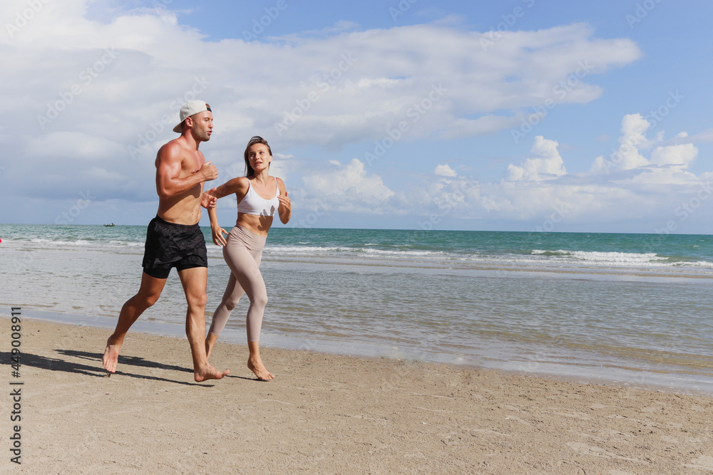 Two buddy runners jogging outdoor on summer tropical island beach with blue sea, couple doing exercise outdoor, sport man and woman jogger athlete doing and training workout outdoor
